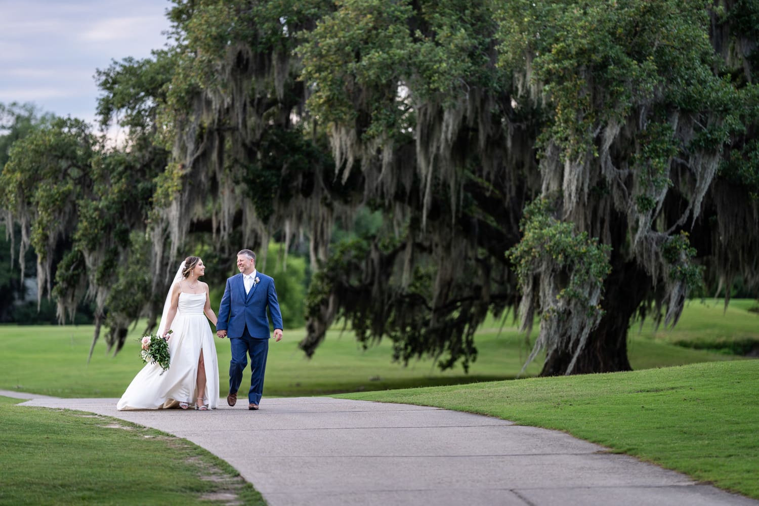 Bride and groom walking along golf cart path at Audubon Golf Clubhouse