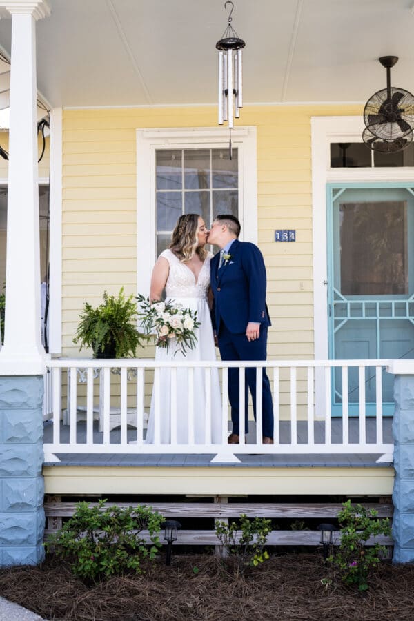 Brides kiss on porch of home in Bay St. Louis