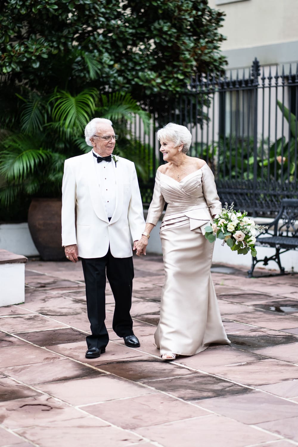 Elderly bride and groom walking through courtyard