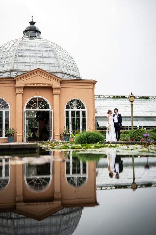 Bride and groom by City Park Conservatory with reflection in lily pond