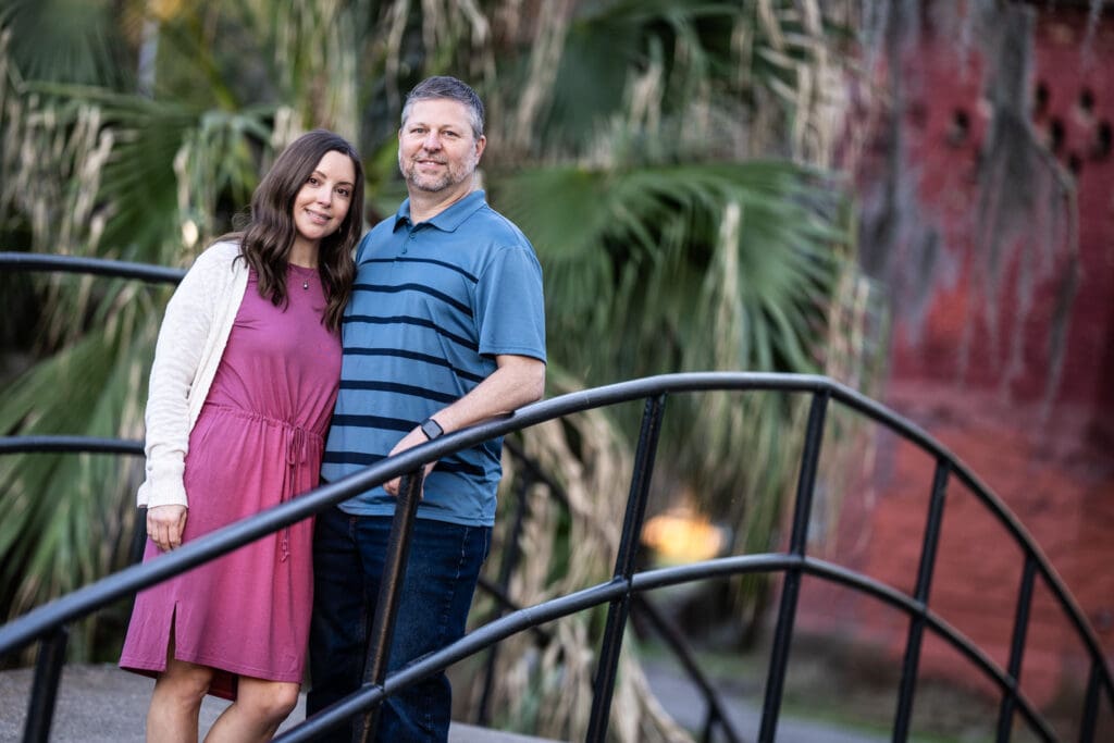 Couple standing on bridge in City Park with red building in the background