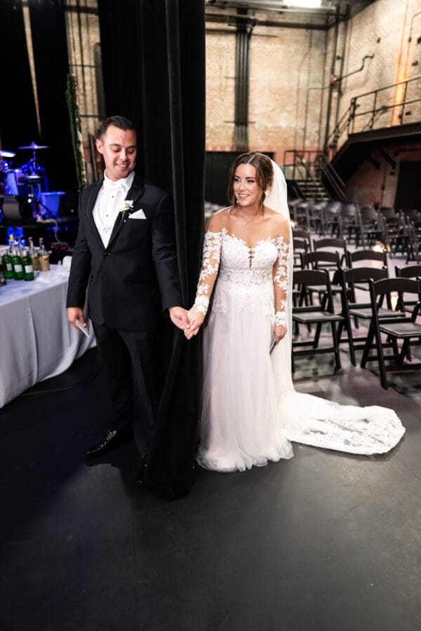 Bride and groom first touch around curtain at Civic Theatre