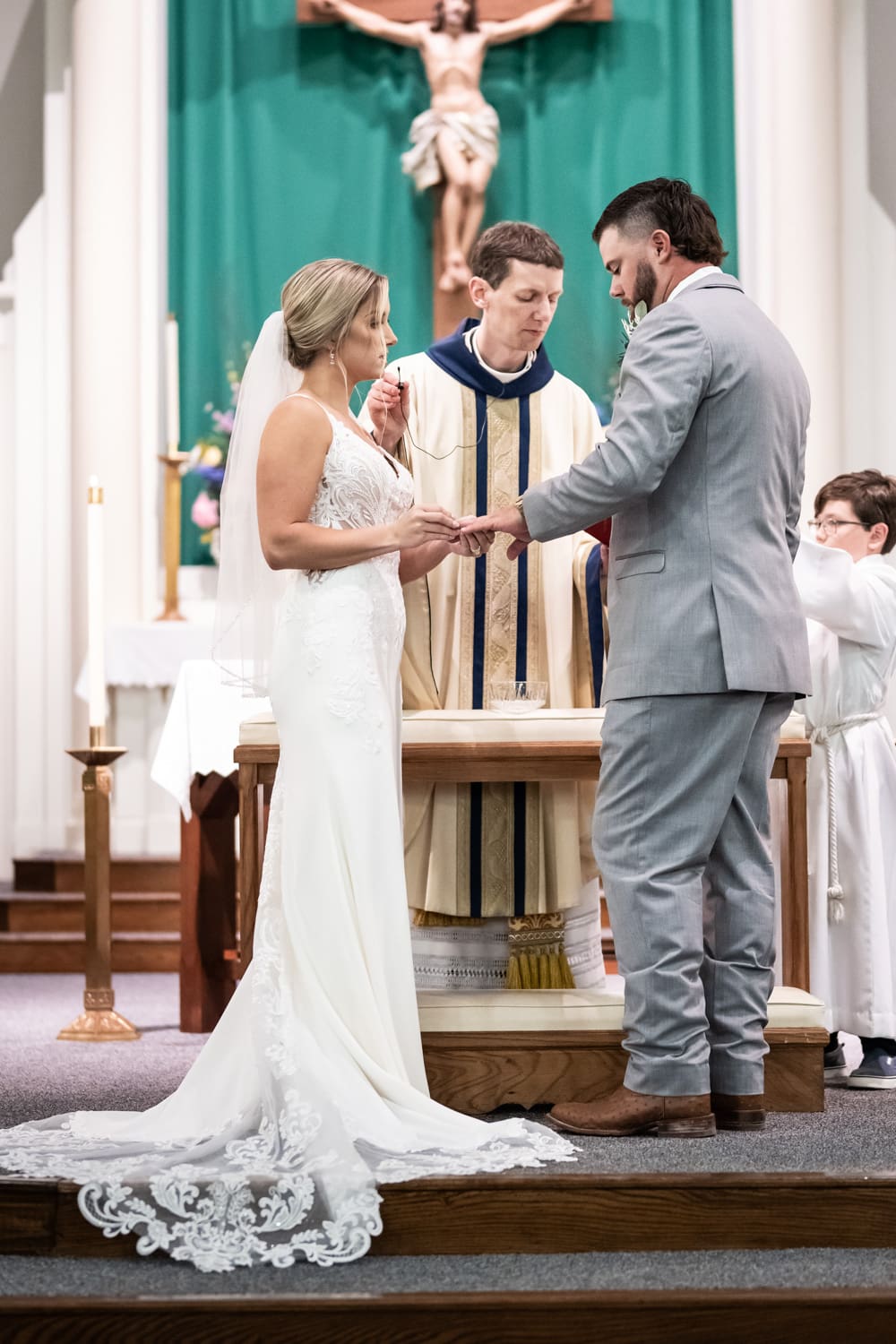 Bride placing ring on groom's finger during wedding ceremony in church