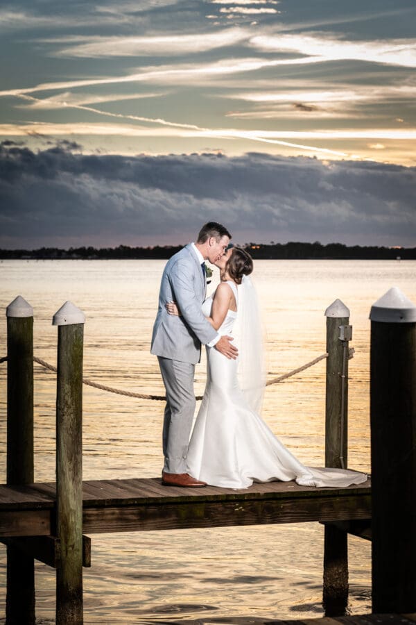 Beach wedding portrait of bride and groom on dock with dramatic sunset