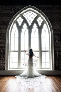 Bride standing in front of large pointed arch window at Felicity Church