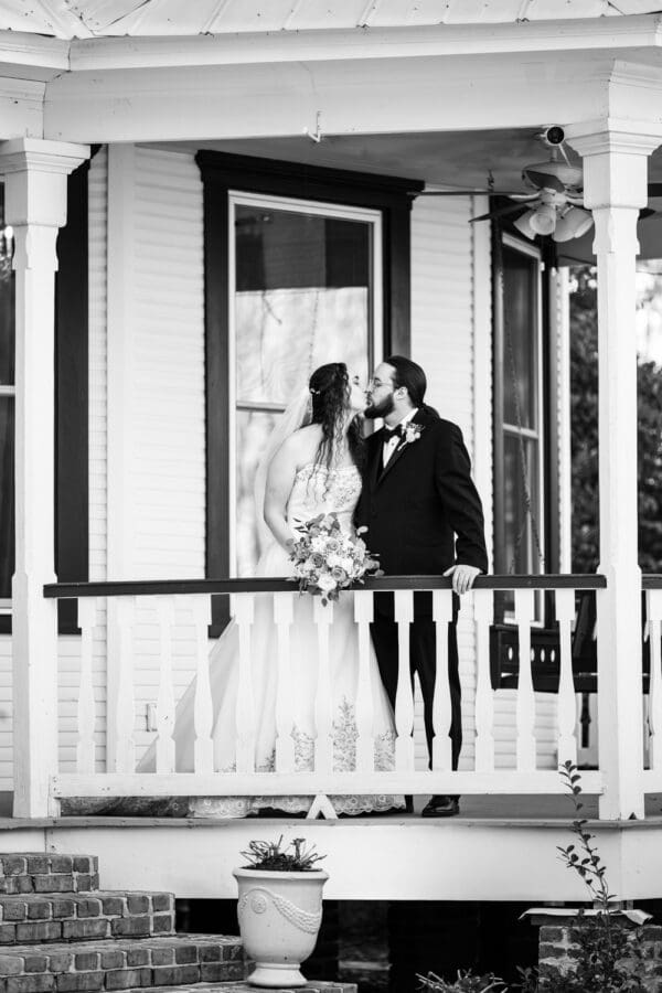 Bride and groom kiss on balcony of Victorian Home at Henry Smith House wedding