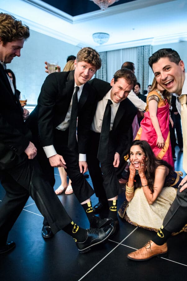 Guys showing off Batman socks at wedding reception