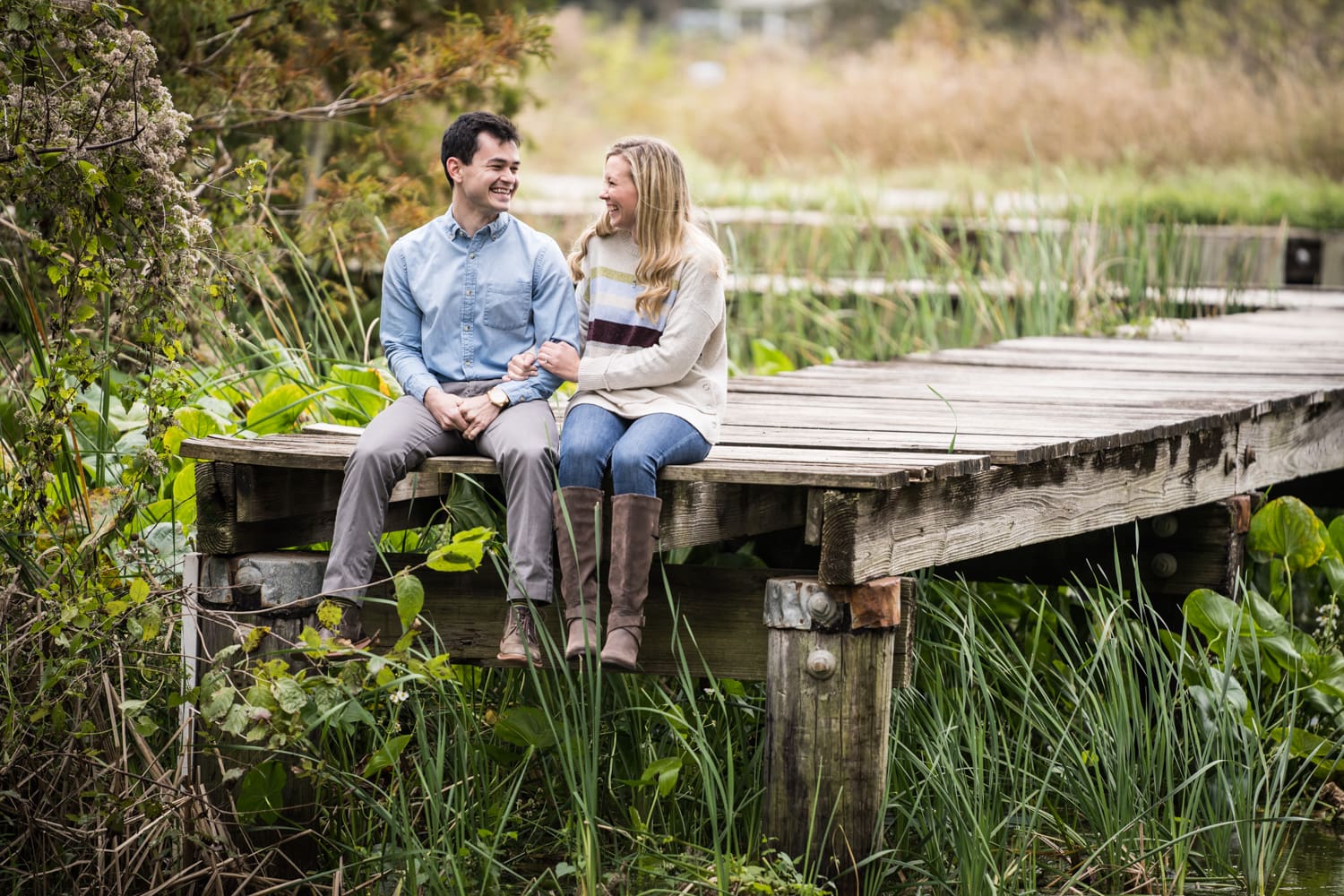 Couple sitting on dock at Lake Martin engagement portrait in Lafayette Louisiana