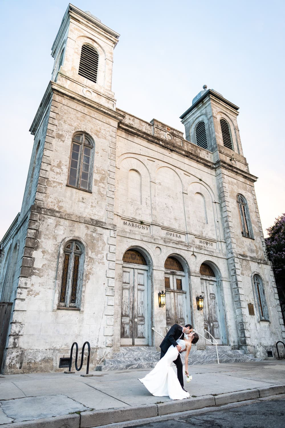 Bride and groom dip and kiss in front of Marigny Opera House