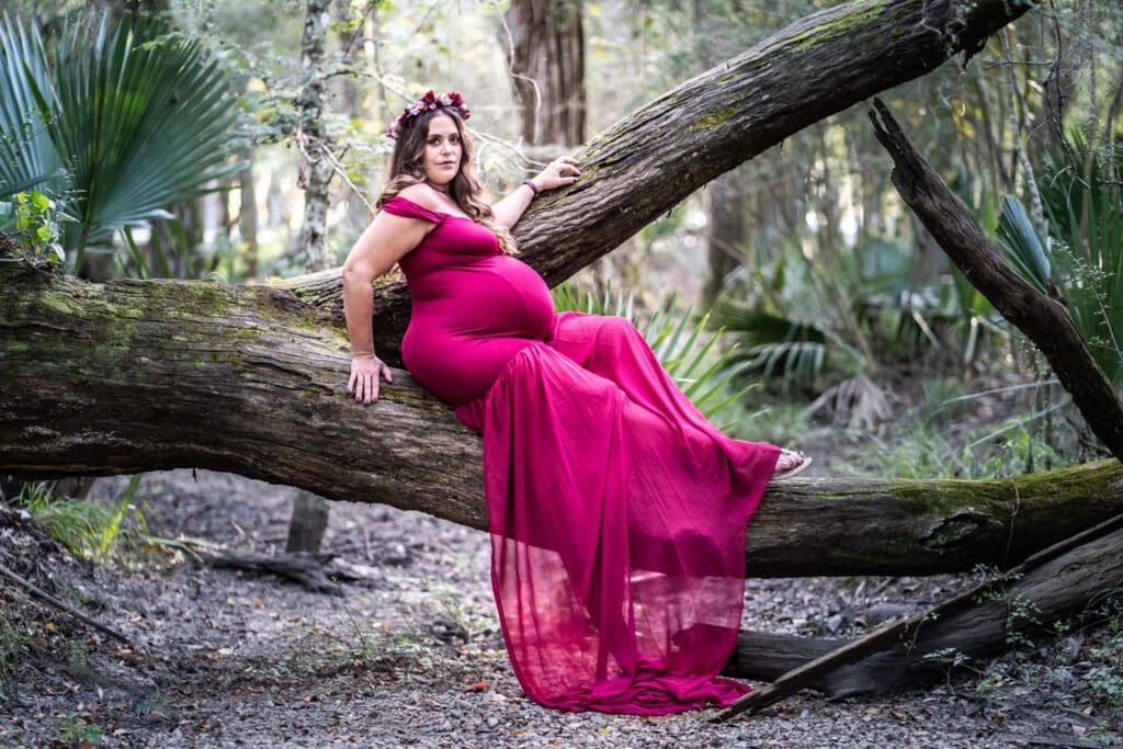 Maternity portrait of mother sitting on downed tree