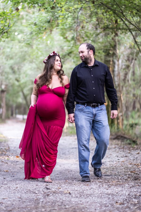 Maternity portrait of mother and father walking through woods in Mandeville