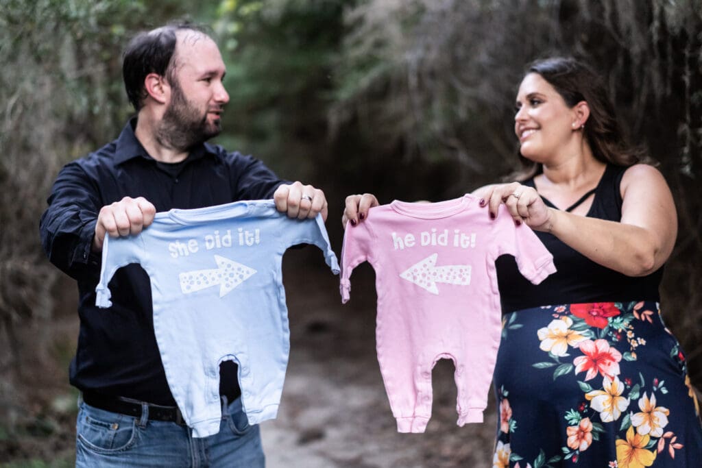 Mother and father holding up baby clothes for twins