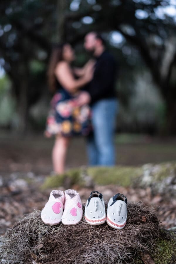 Close-up of baby shoes with mother and father in the background