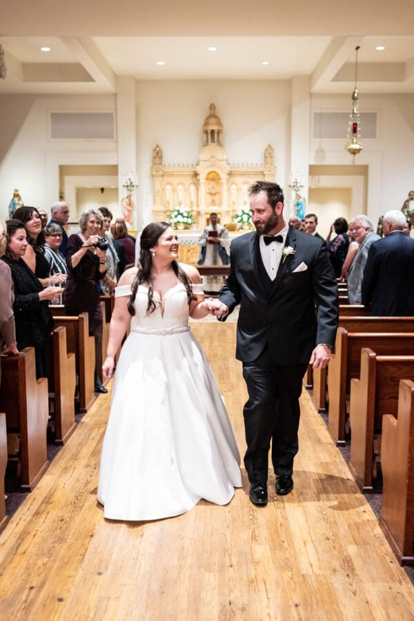 Smiling bride and groom walk down the aisle at end of wedding