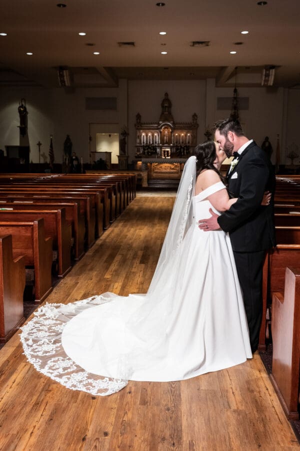 Bride and groom kiss in aisle of church
