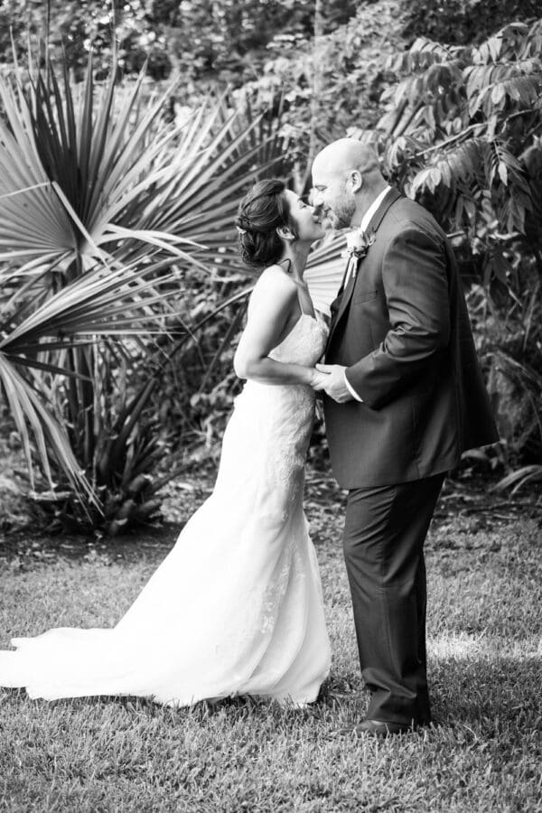 Bride and groom kiss with foliage in the background