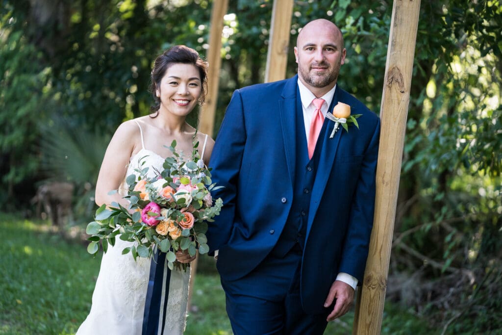 Bride and groom standing by wood columns