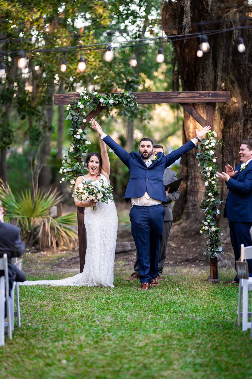 Couple raises arms in celebration at their Palmettos on the Bayou wedding in Slidell