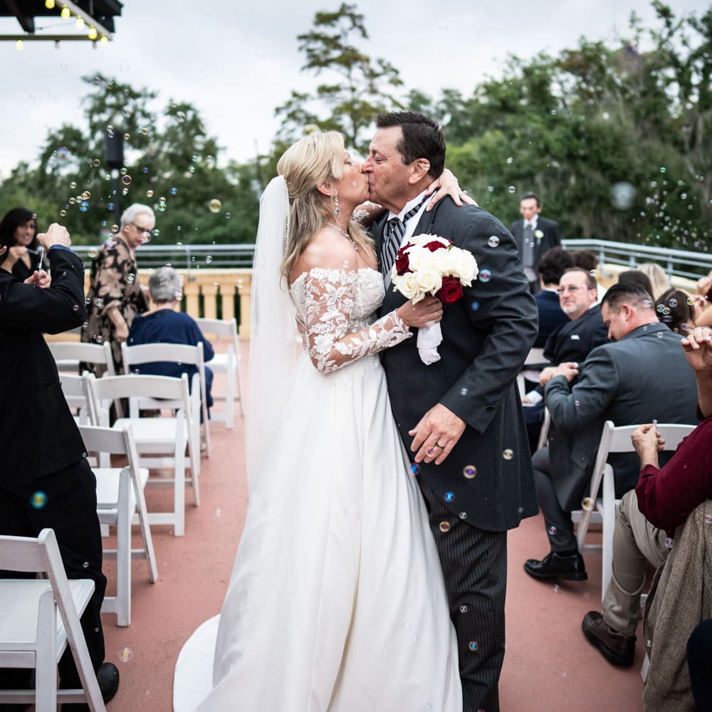 Bride and groom kiss amongst bubbles at end of wedding ceremony at Parkview Terrace in City Park