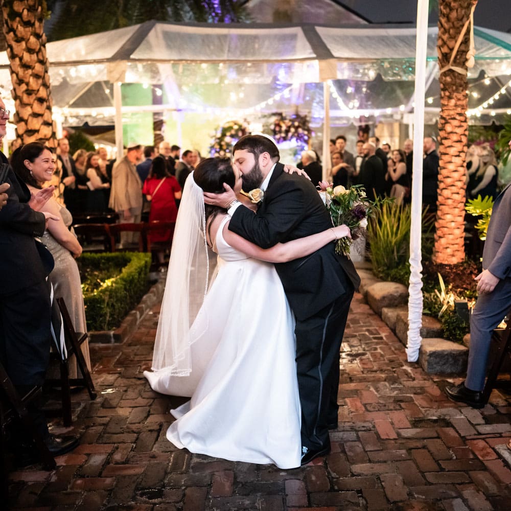 Bride and groom kiss at end of Race and Religious wedding ceremony