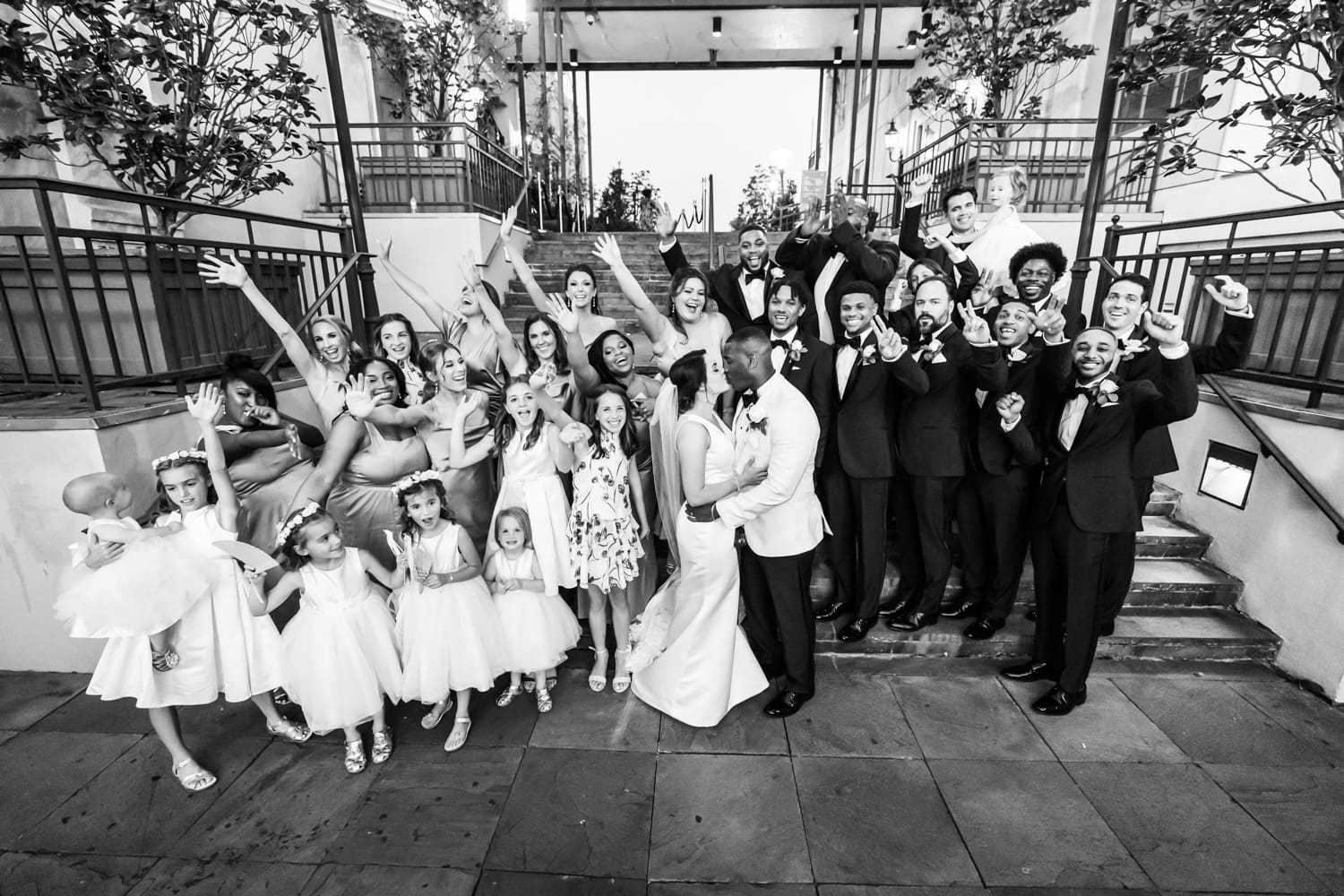 Bride and groom celebrate with wedding party on steps of Jax Brewery building