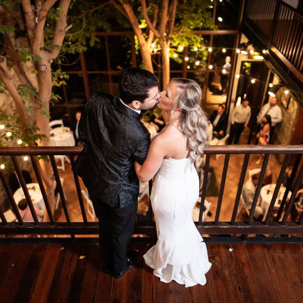 Bride and groom kiss on balcony at Rosy's Jazz Hall wedding