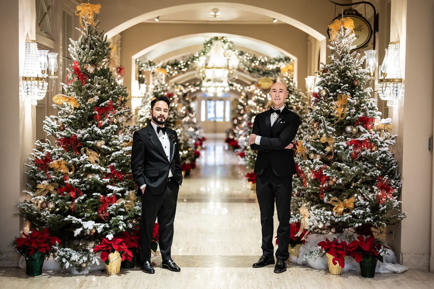 Two grooms in Christmas-decorated Royal Sonesta Hotel lobby.