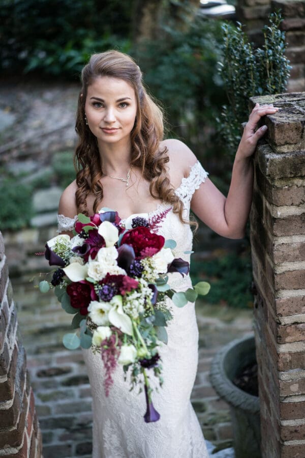 Bride stands near brick entrance to courtyard