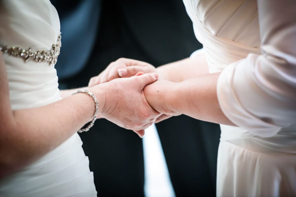 Brides holding hands during ceremony