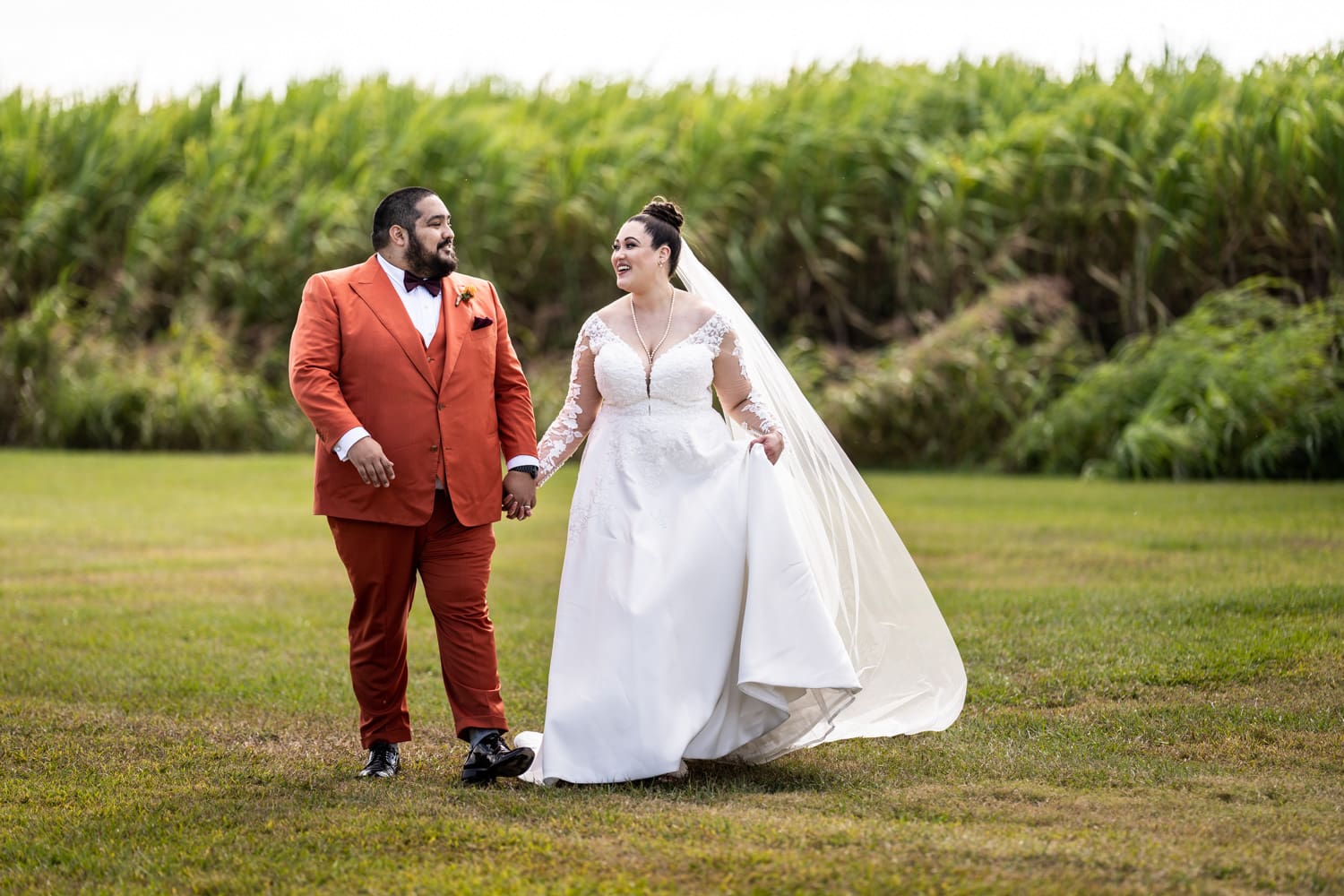 Bride and groom walking in front of sugar cane field