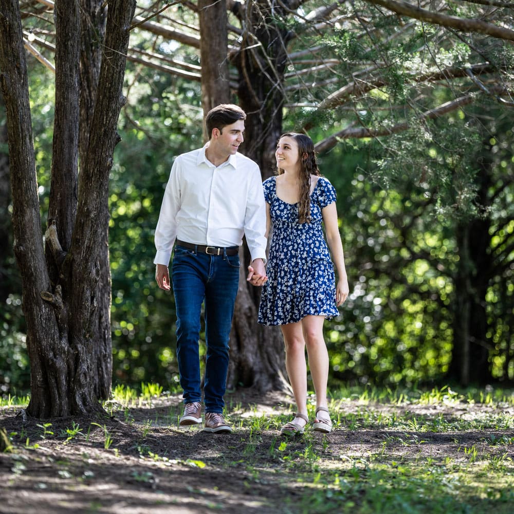 Engagement portrait of couple walking through wooded area at The Villa wedding venue in Picayune Mississippi