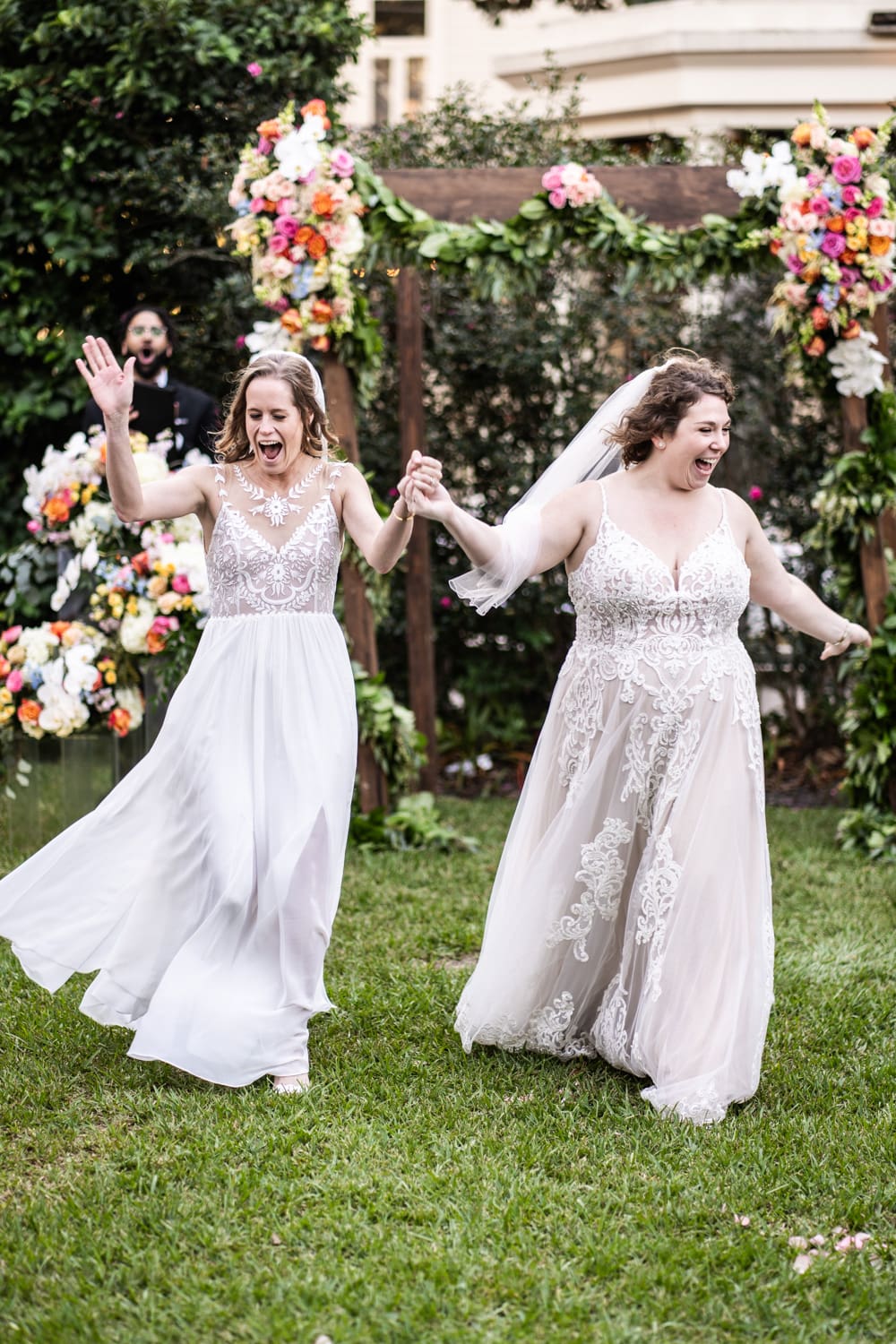 Two brides celebrate at the end of their wedding ceremony at The Elms Mansion