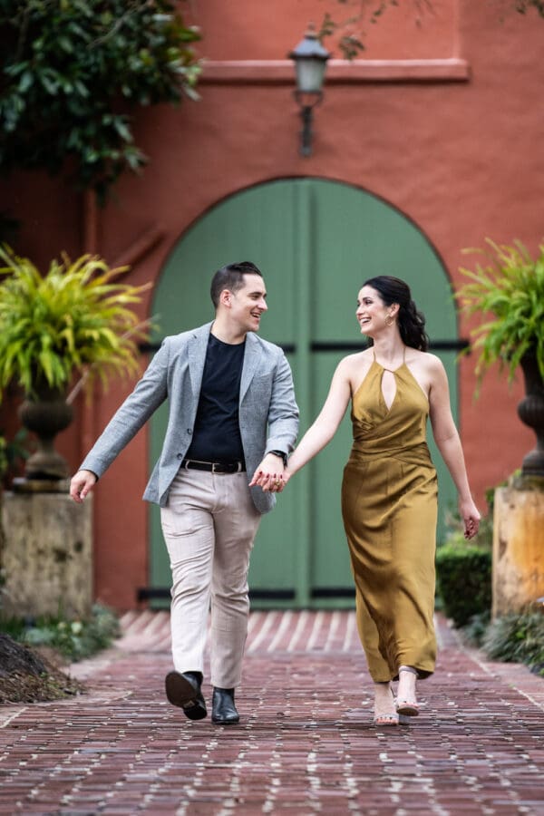 Houmas House engagement portrait of couple walking down brick pathway in garden