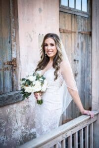 Bride at Race and Religious, standing on balcony with hand on rail.