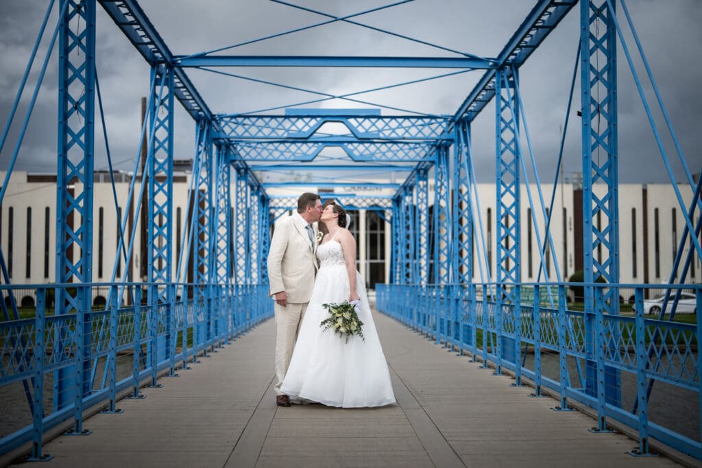 Bride and groom kissing on blue Magnolia Bridge over Bayou St. John
