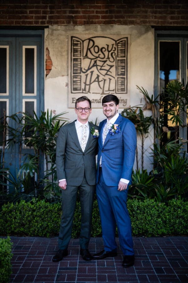 Grooms standing in front of Rosy's Jazz Hall sign