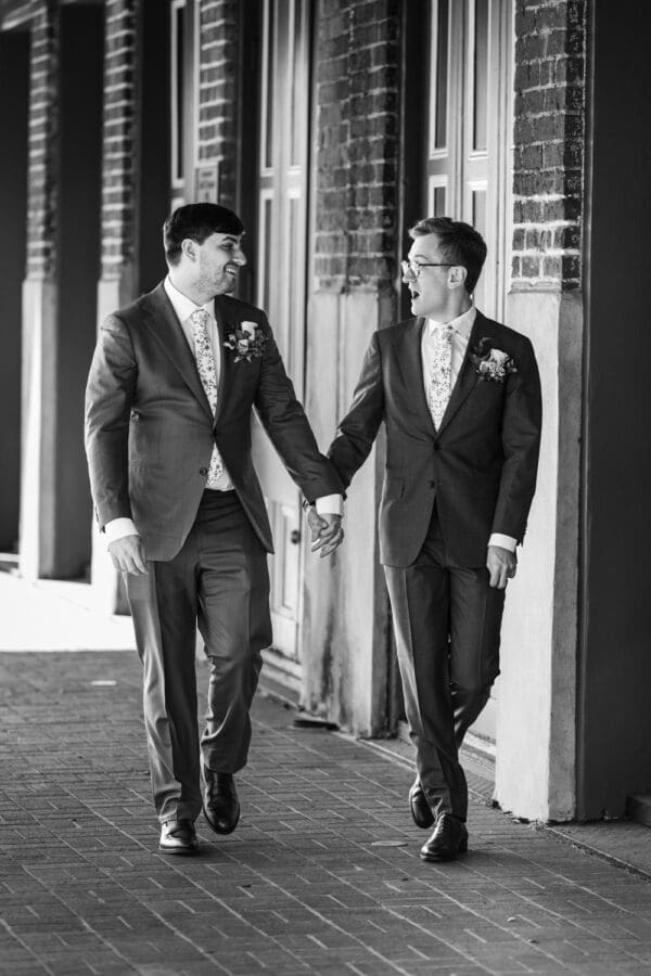 Two grooms walking down sidewalk