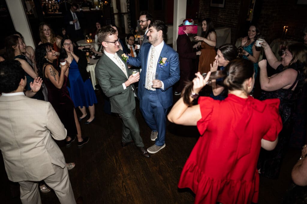 Grooms on dance floor with guests