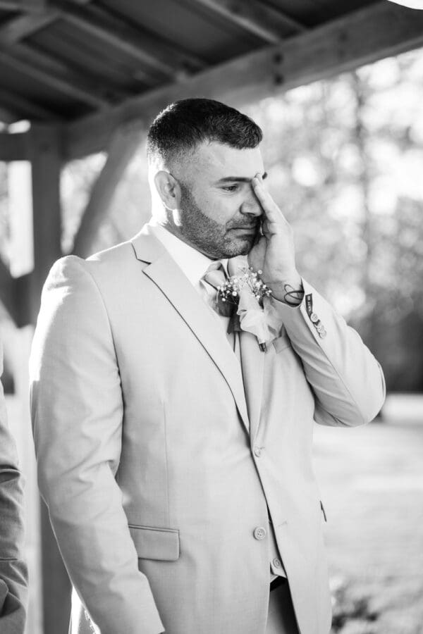 Groom wipes tear from his eye as he sees bride coming up the aisle
