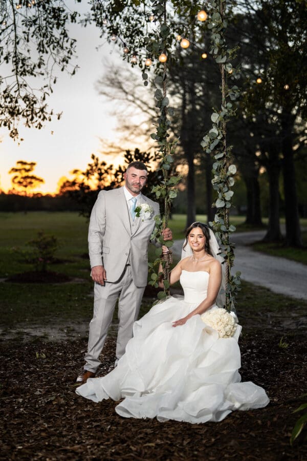 Bride and groom on tree swing with sunset in the background