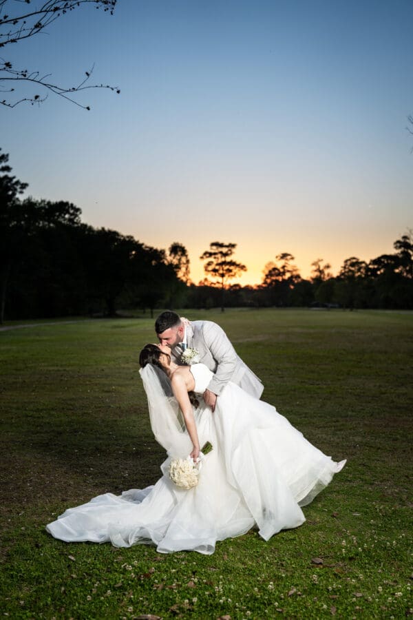 Bride and groom kiss with golf course and sunset in the background