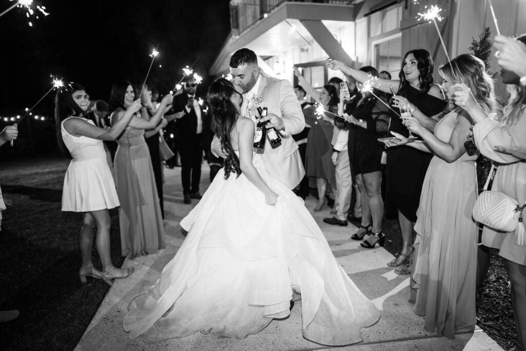 Bride and groom kiss during sparkler send-off at the Sadie Jane