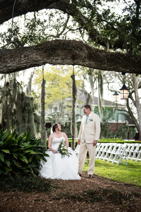 Groom looking at bride sitting on tree swing at Southern Oaks