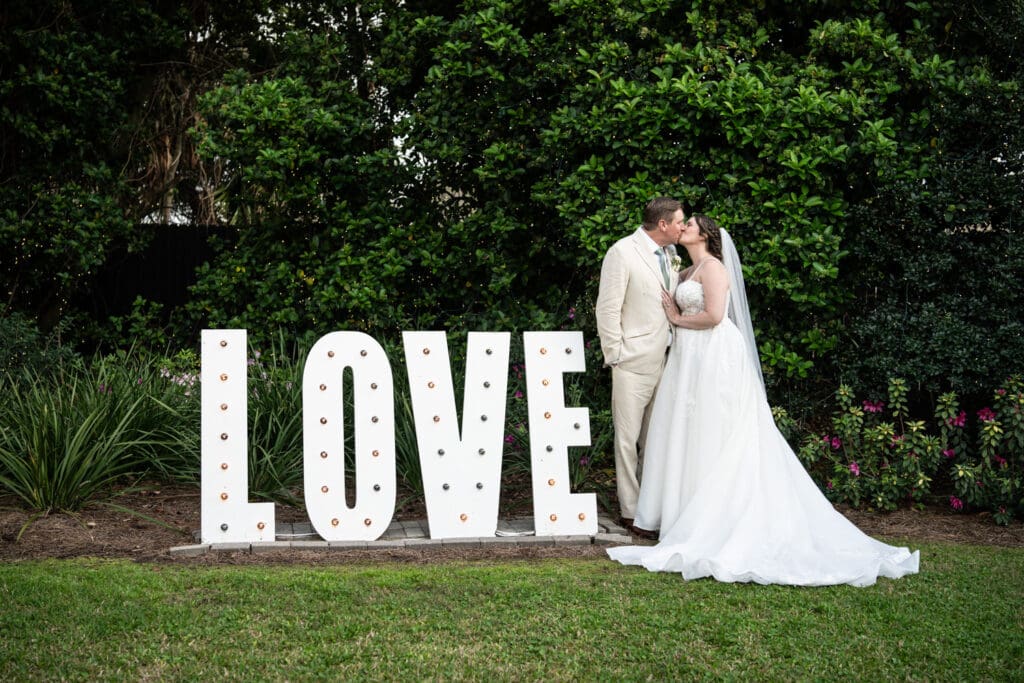 Couple kisses by Love sign at Southern Oaks