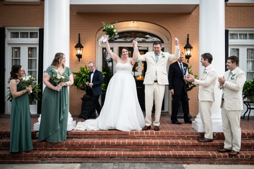 Bride and groom raise arms in celebration at conclusion of wedding ceremony