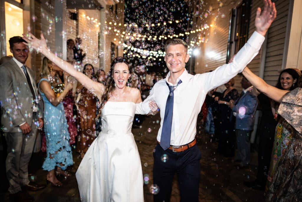 Bride and groom exit through shower of bubbles at Degas House wedding