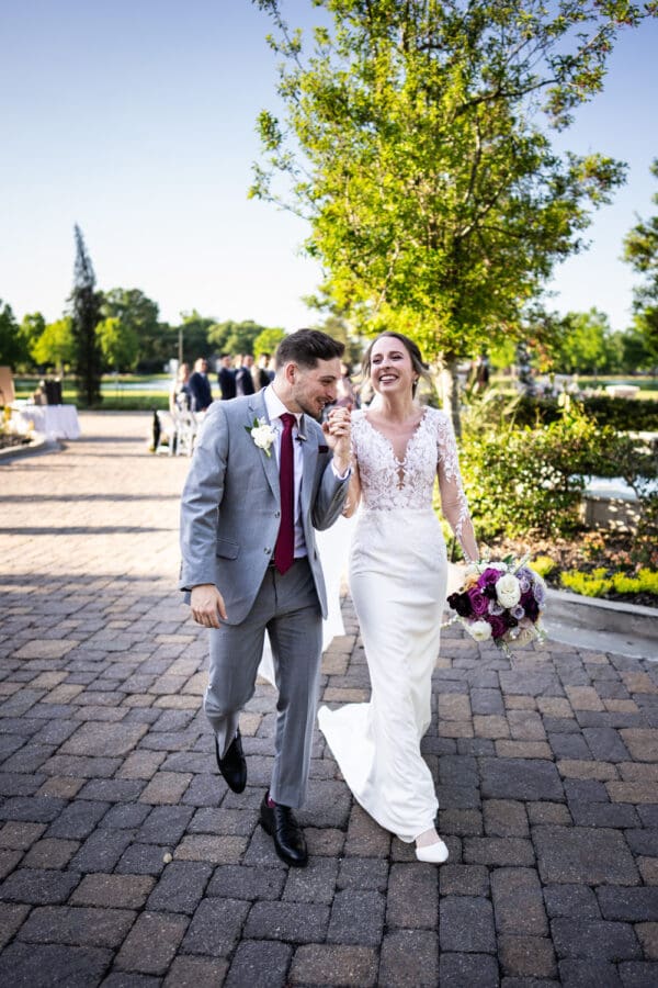 Groom kisses bride's hand as they walk down the aisle