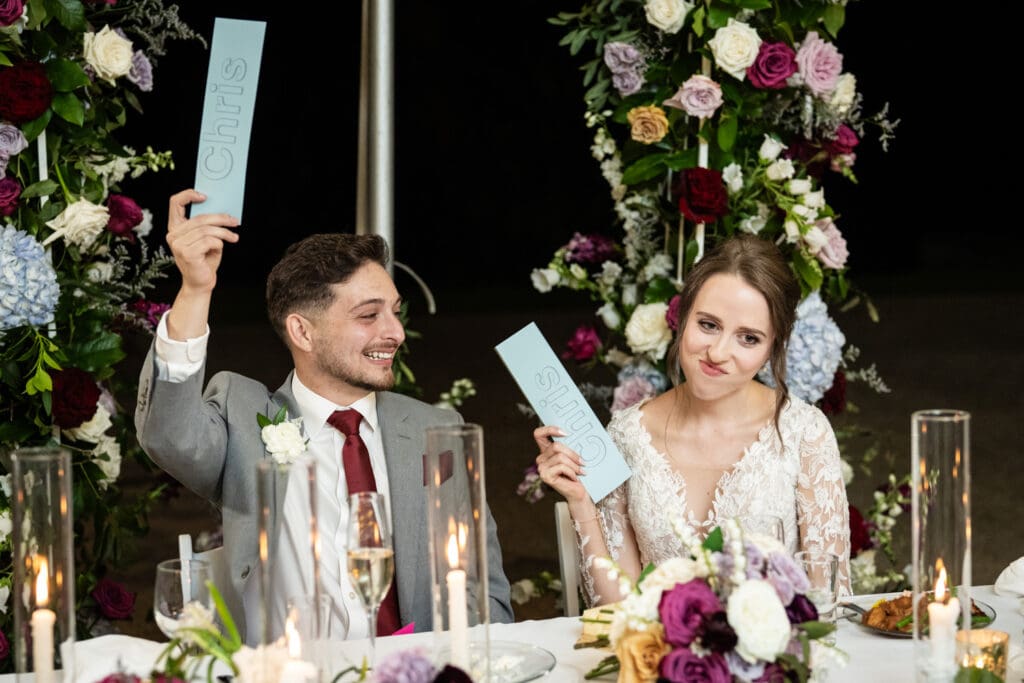 Bride and groom holding up cards as they play game