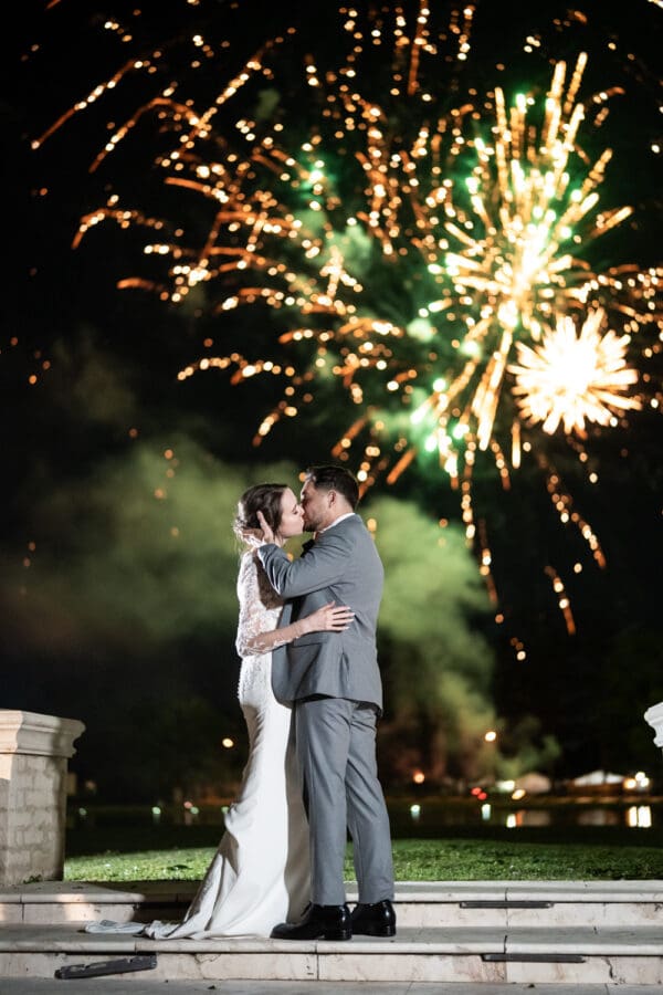 Bride and groom kiss with fireworks in the background at Ponchatoula 22 estate