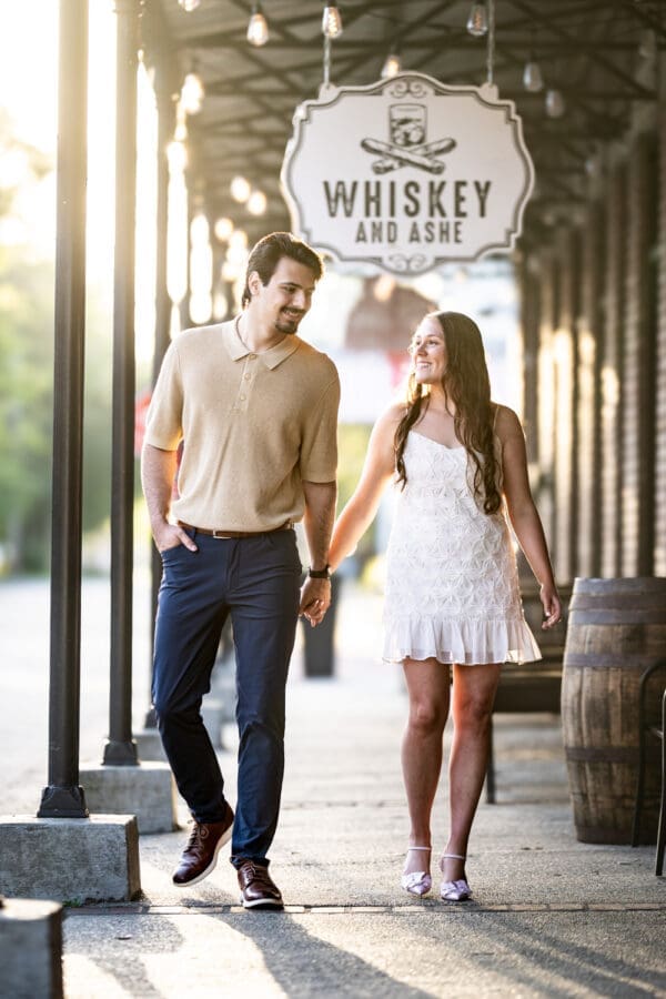 Couple walking along sidewalk in Olde Town Slidell with brilliant sunlight behind them